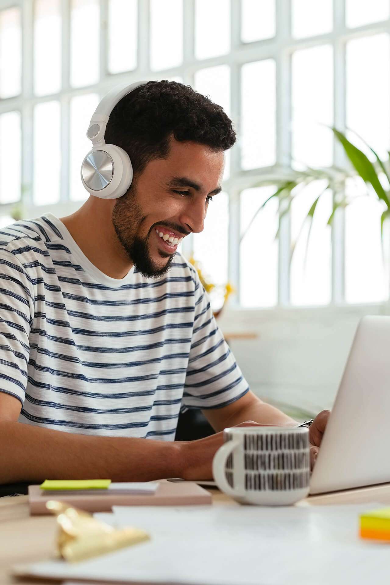 man wearing headphones smiling at his laptop