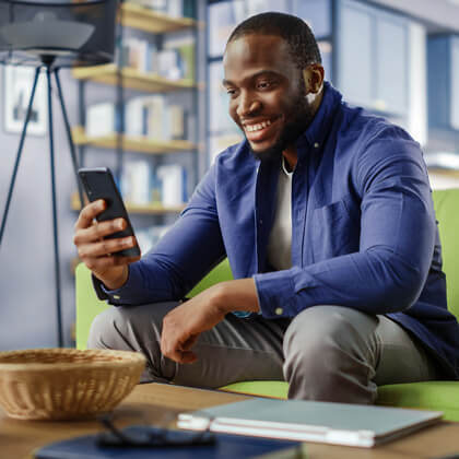 man sitting on a couch scrolling his phone