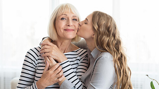 daughter hugs and kisses Gram on the cheek for Mothers Day