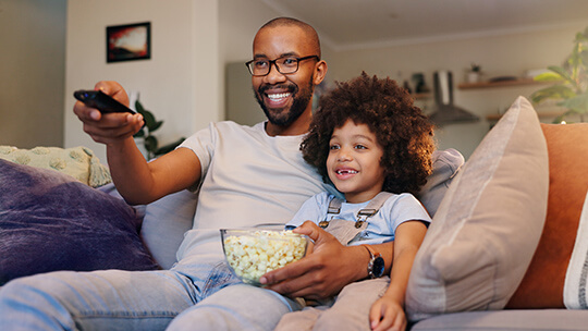 Dad and kid watch shows on tv together