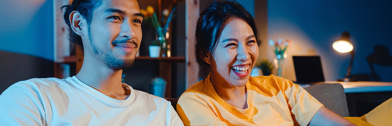 Smiling couple on sofa watching TV